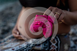 Happy pregnant woman sitting on the beach with baby shoes