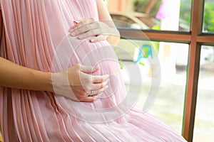 Happy pregnant woman sitting on chair at home.