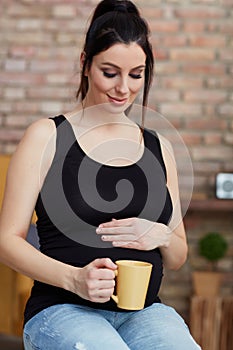 Happy pregnant woman sitting at home