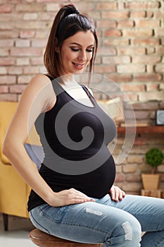 Happy pregnant woman sitting at home