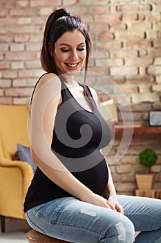 Happy pregnant woman sitting at home