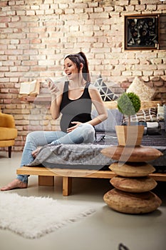 Happy pregnant woman sitting at home