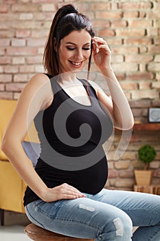 Happy pregnant woman sitting at home