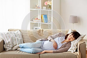 Happy pregnant woman sleeping on sofa at home