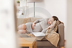 Happy pregnant woman sleeping on sofa at home