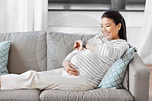 happy pregnant woman with smart watch at home