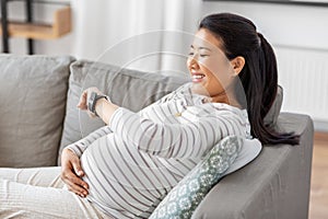 happy pregnant woman with smart watch at home