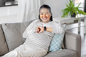 happy pregnant woman with smart watch at home
