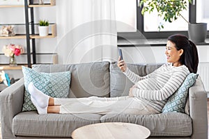 happy pregnant woman with smartphone at home