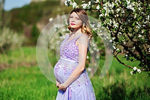 Happy pregnant woman in spring blossom garden