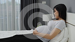 Happy pregnant woman stroking her belly on bed