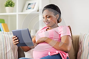 Happy pregnant woman with tablet pc at home