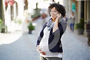 Happy pregnant woman talking on the phone