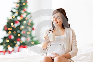 Happy pregnant woman with tea cup at christmas