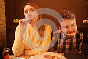 Happy pregnant woman with teenager boy eating pizza and enjoy it with savor. friends loves fast food. dinner in the