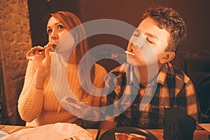 Happy pregnant woman with teenager boy eating pizza and enjoy it with savor. friends loves fast food. dinner in the