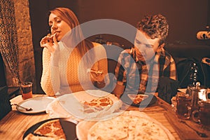 Happy pregnant woman with teenager boy eating pizza and enjoy it with savor. friends loves fast food. dinner in the