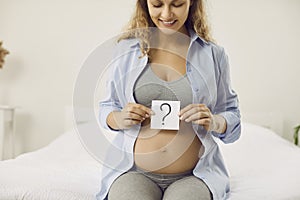 Happy pregnant woman thinking of name or trying to guess gender of her unborn baby