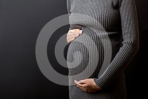 Happy pregnant woman touching her abdomen at Colored background. Future mother is wearing white underwear. Expecting of