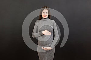 Happy pregnant woman touching her abdomen at Colored background. Future mother is wearing white underwear. Expecting of a baby.