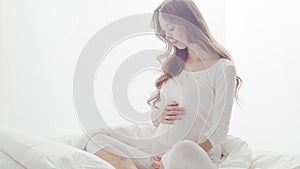 Happy pregnant woman touching her beautiful belly. Pregnancy, motherhood, and expectation concept