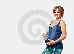 Happy pregnant woman touching her belly with hands.