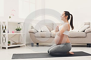 Happy pregnant woman training yoga in hero pose