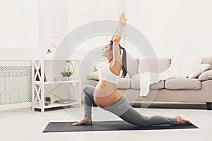 Happy pregnant woman training yoga in hero pose