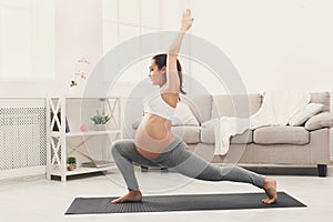 Happy pregnant woman training yoga in hero pose