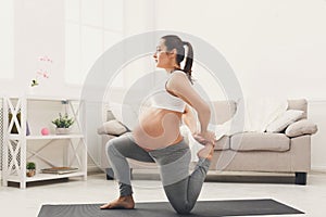 Happy pregnant woman training yoga at home