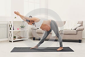 Happy pregnant woman training yoga at home