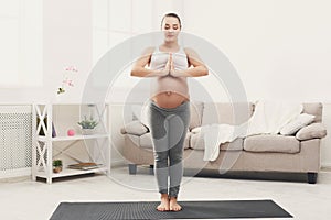 Happy pregnant woman training yoga at home