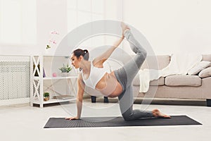 Happy pregnant woman training yoga at home