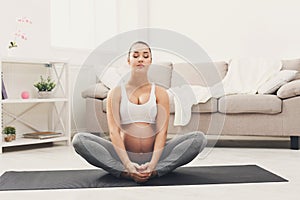 Happy pregnant woman training yoga in lotus pose