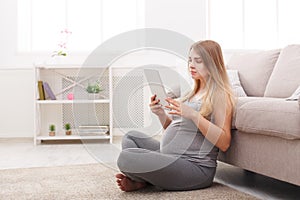 Happy pregnant woman using digital tablet.