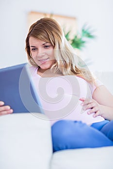 Happy pregnant woman using tablet