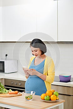 Happy pregnant woman using voice command recorder on smartphone