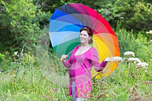 Happy pregnant woman walking under a colorful umbrella