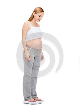 Happy pregnant woman weighting herself