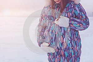 Happy pregnant woman in winter warm clothes in outdoor.