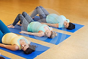 Happy pregnant women exercising on mats in gym