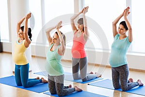 Happy pregnant women exercising on mats in gym