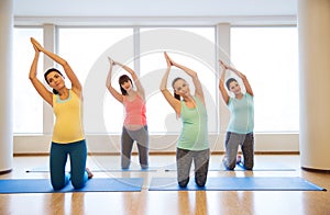 Happy pregnant women exercising on mats in gym