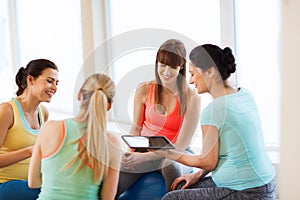 Happy pregnant women with gadgets in gym