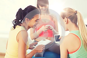 Happy pregnant women with gadgets in gym