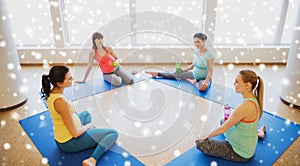 Happy pregnant women sitting on mats in gym