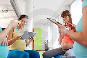 Happy pregnant women with tablet pc in gym