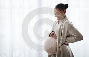 Happy pregnant young black woman touching her belly