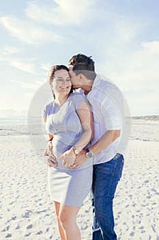 Happy pregnant young couple interacting and having fun, standing outdoors