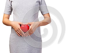 Happy pregnant young  woman making hand heart gesture and holding red heart in hand in front of mother belly. prenatal, pregnancy